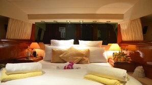Una habitación de hotel bien iluminada con una cama grande, dos mesitas de noche y un espejo sobre la cama.