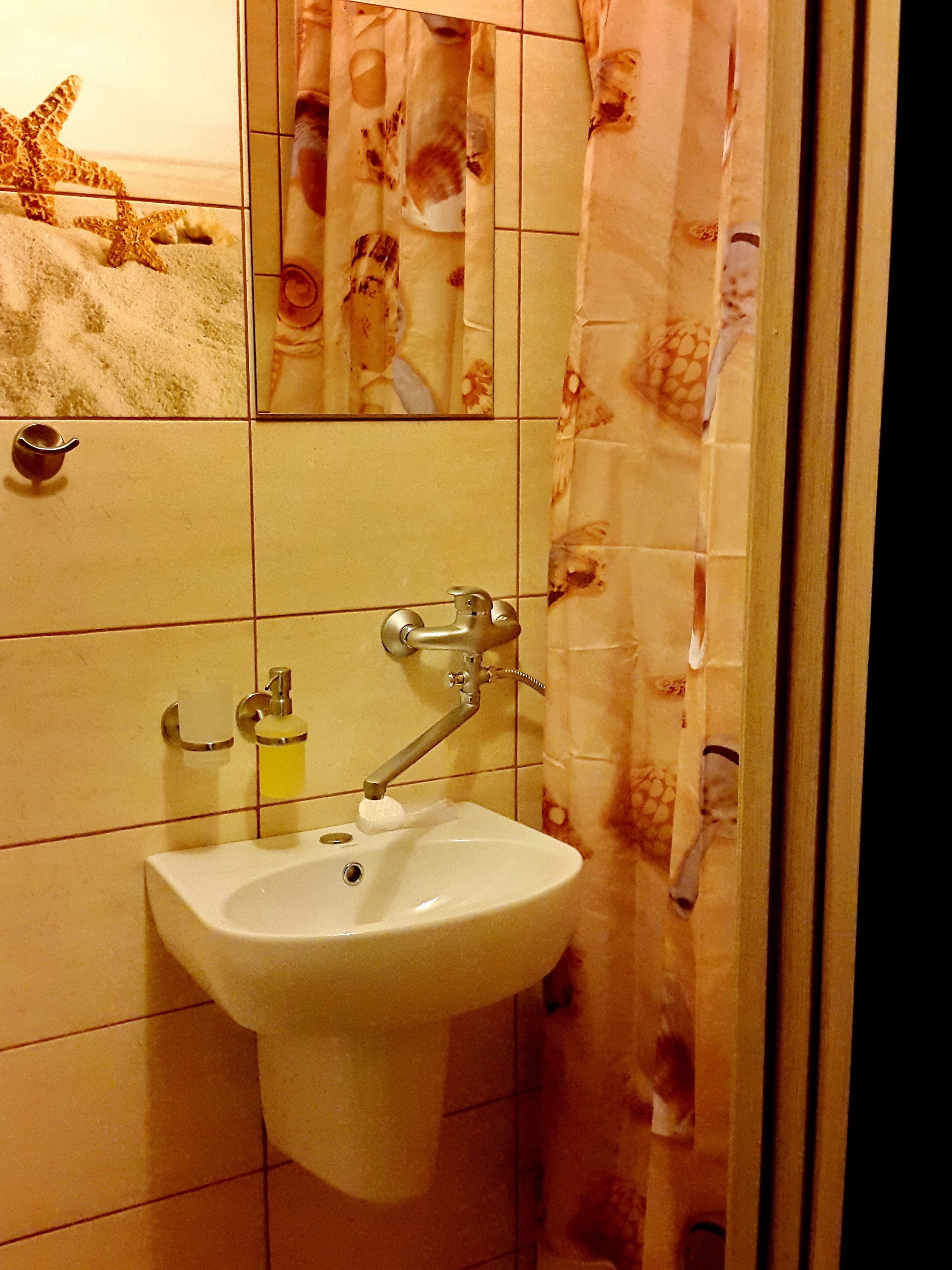 Un baño con lavamanos, espejo y paredes de azulejos.