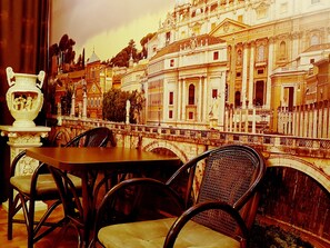 A dining area with a table and chairs, a decorative vase, and a mural of a historic building. - Chernigov ApartLux (Chernihiv)