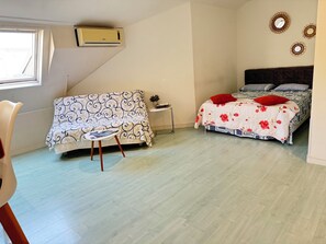 A bedroom with a bed, a sofa, a small table, and a window. - Loft for 2–4 people, Place du Diamant, downtown, with garage. (Ajaccio)