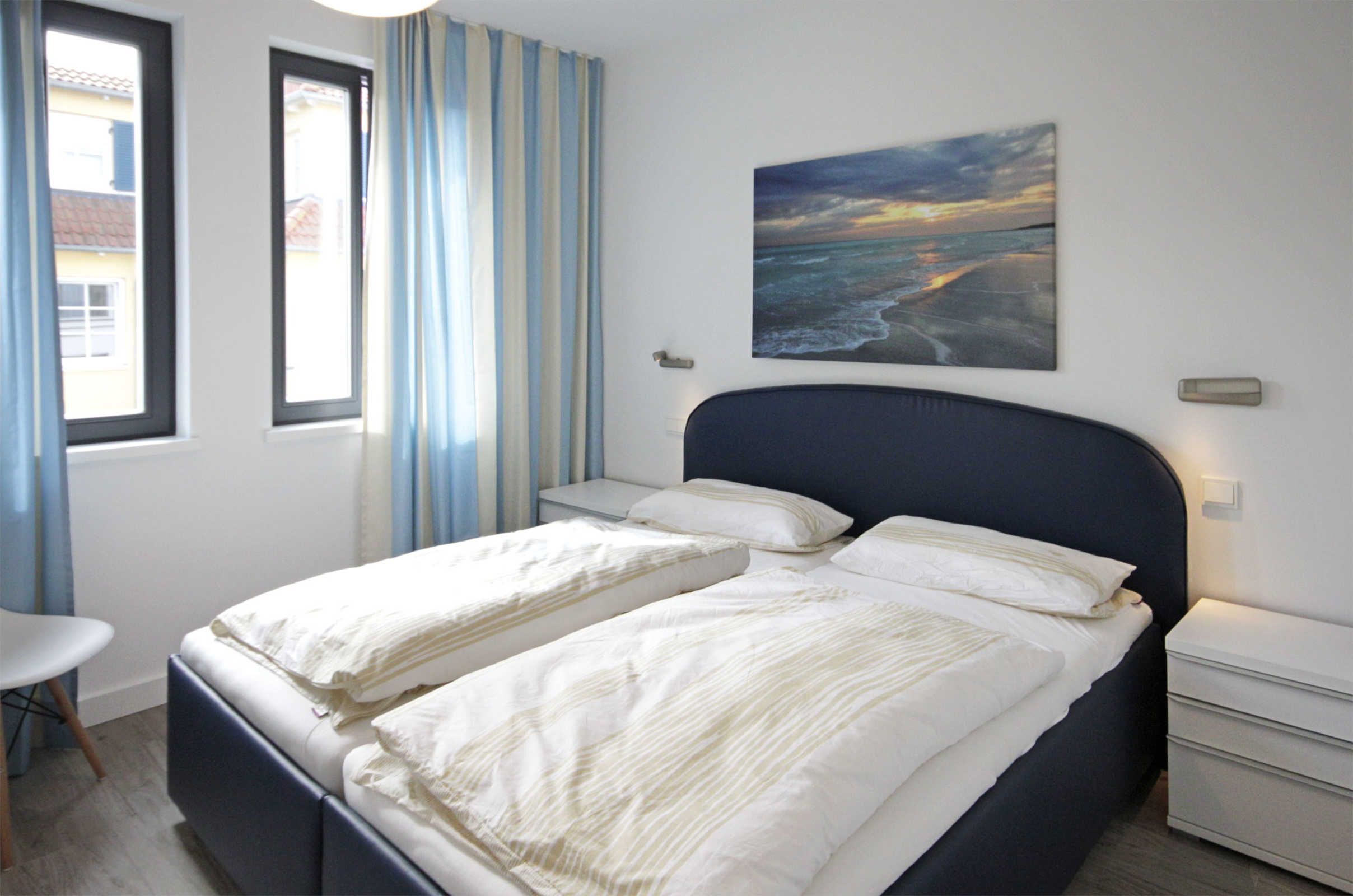 Un dormitorio con dos camas, una mesita de noche, una silla y una ventana con cortinas.