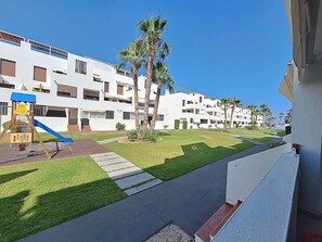 A residential building with a playground, palm trees, and a clear sky. - AL 133 - Apartment with WiFi and parking in Vera Playa (Vera playa)