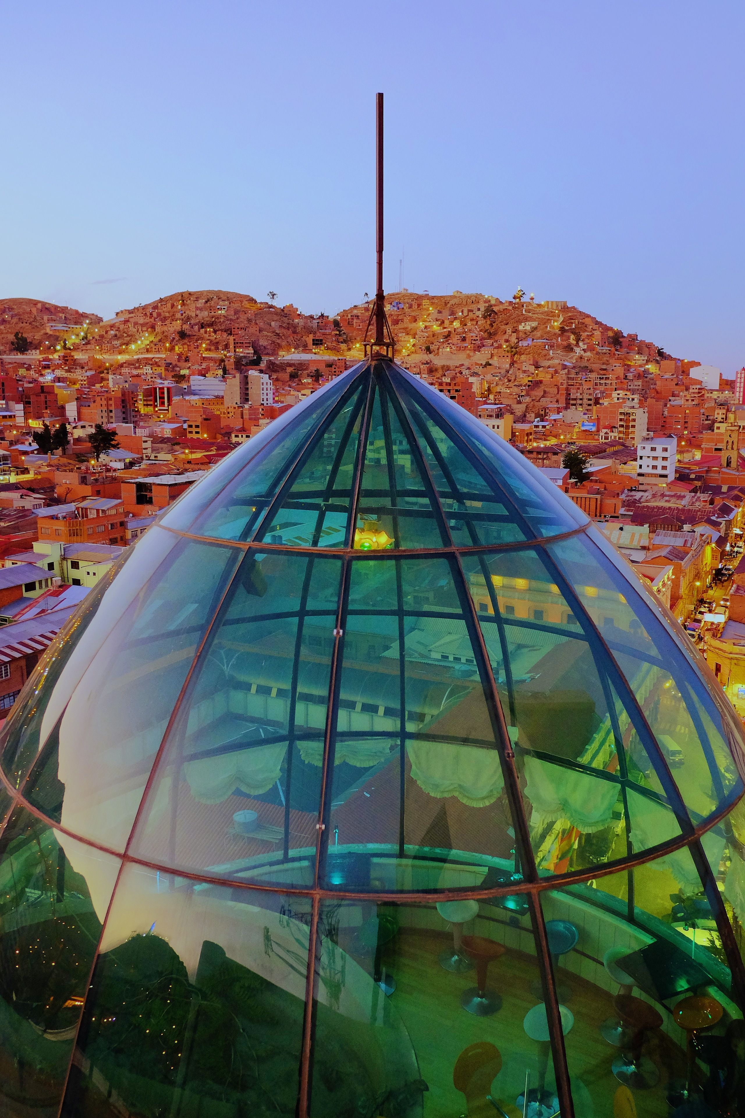 Una estructura moderna con cúpula de cristal y un eje central, rodeada por una zona urbana densamente poblada con edificios.