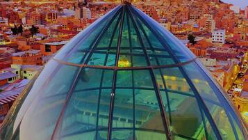 Una estructura moderna con cúpula de cristal y un eje central, rodeada por una zona urbana densamente poblada con edificios.