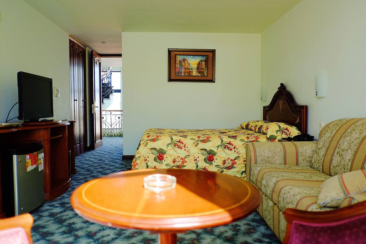 Ein Hotelzimmer mit Bett, einer Couch, einem Fernseher und einem kleinen Tisch.