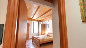 Un dormitorio con techo de madera, una cama y una ventana.