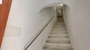 Una escalera con paredes blancas y una puerta de madera a la izquierda.
