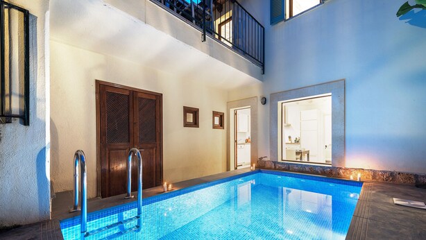 Ein Innenpool mit Fliesenboden, einer Holztür und einem Balkon mit Geländer.
