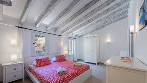 Ein Schlafzimmer mit einem großen Bett, weißen Nachttischen, einem Kleiderschrank und einem Schreibtisch.
