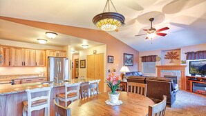 A spacious kitchen with wooden cabinets, a central island with bar stools, a dining table, and a ceiling fan. - Alpine Villagers (Leavenworth)
