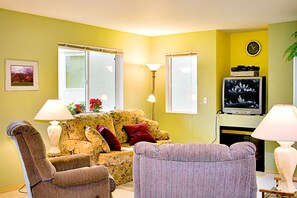 A living room with a sofa, armchairs, a television, and a fireplace.