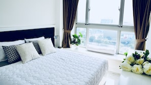 Una habitación de hotel moderna con una cama grande, vista a la ciudad y una planta en maceta.