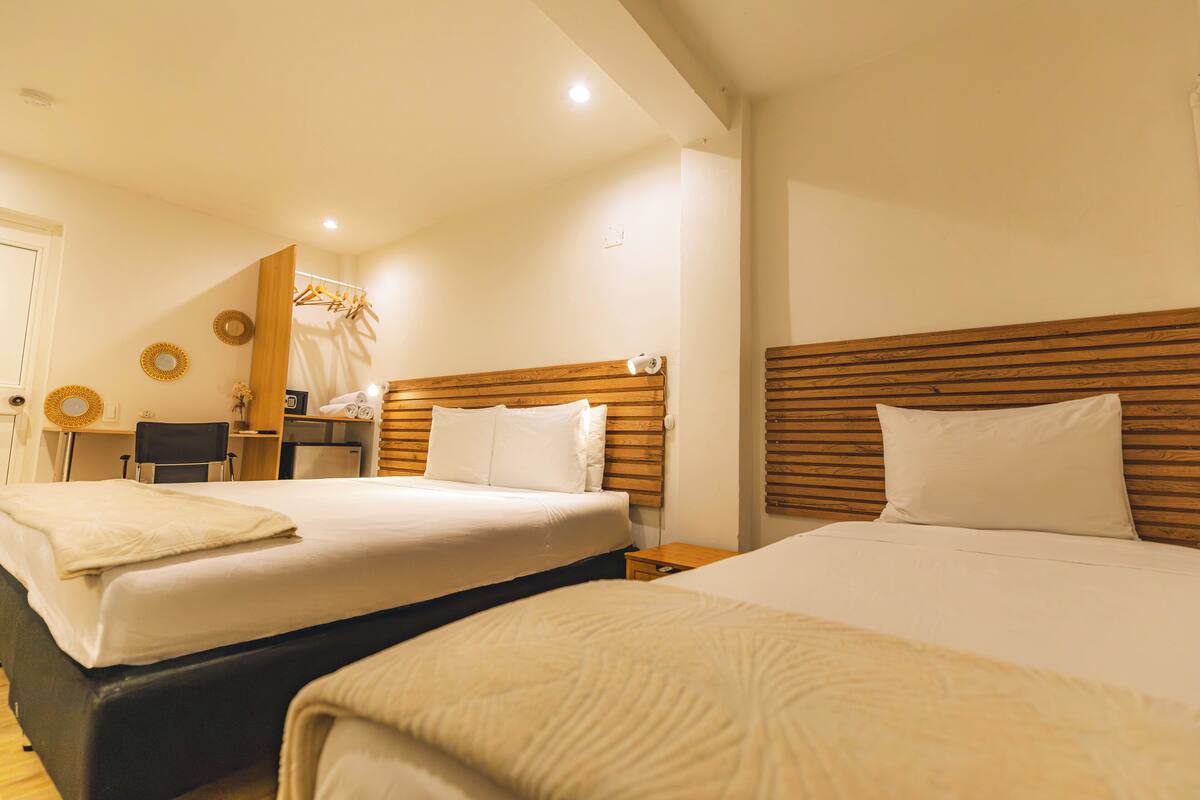A hotel room with two beds, a desk, and a chair.