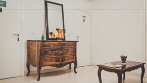 A room with a wooden dresser, a small table with a glass, and a mirror. - Il Gattopardo (Florence)