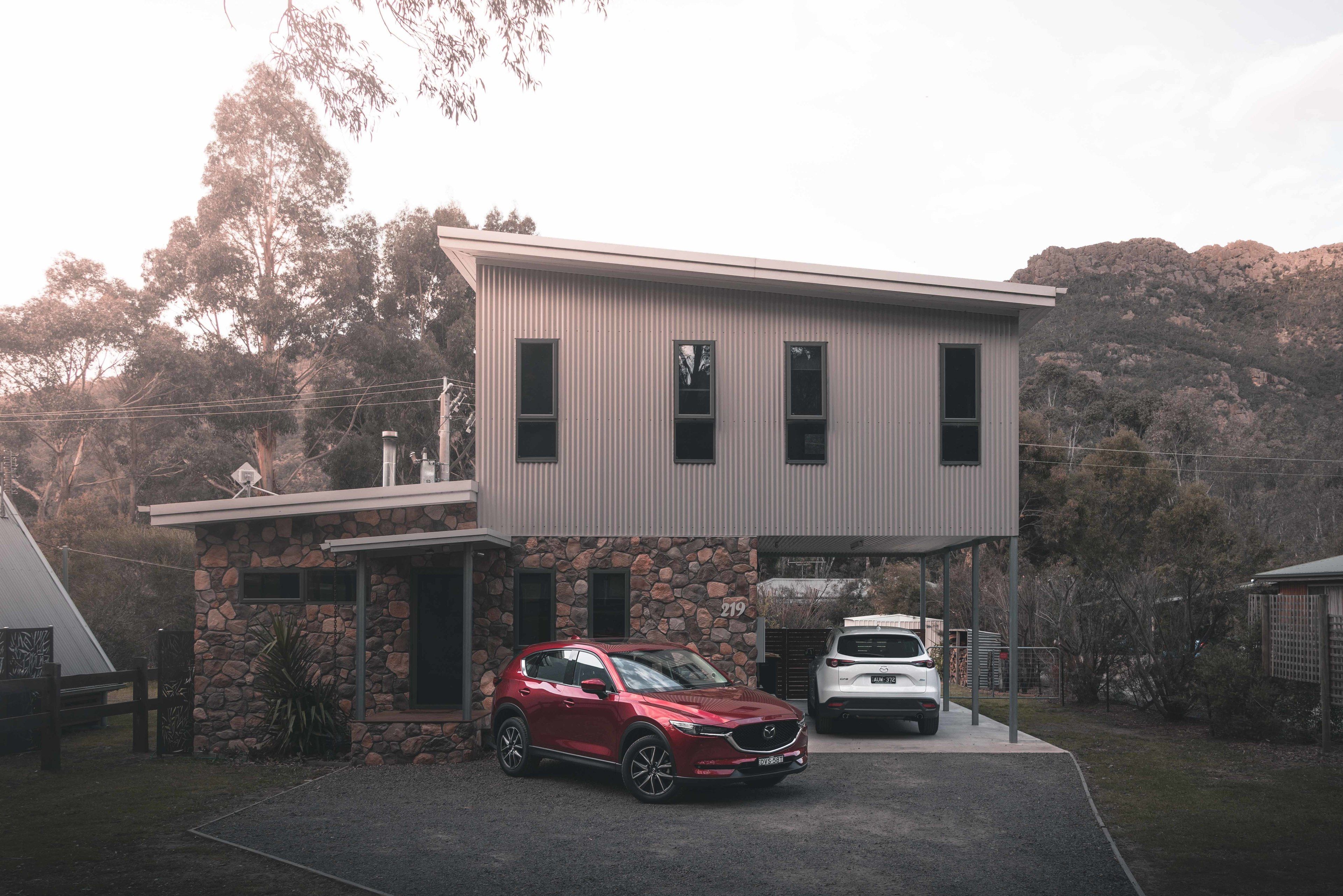 A modern two-story house with a stone foundation and a flat roof.