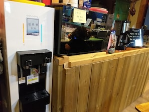Eine Kaffeemaschine, ein Kühlschrank und eine Theke mit einer Holzwand.