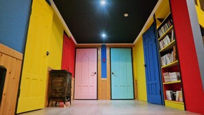 Un couloir avec des portes colorées et une bibliothèque.