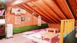 Une pièce mansardée chaleureuse avec des poutres apparentes, un radiateur, un lit en bois et une petite table.