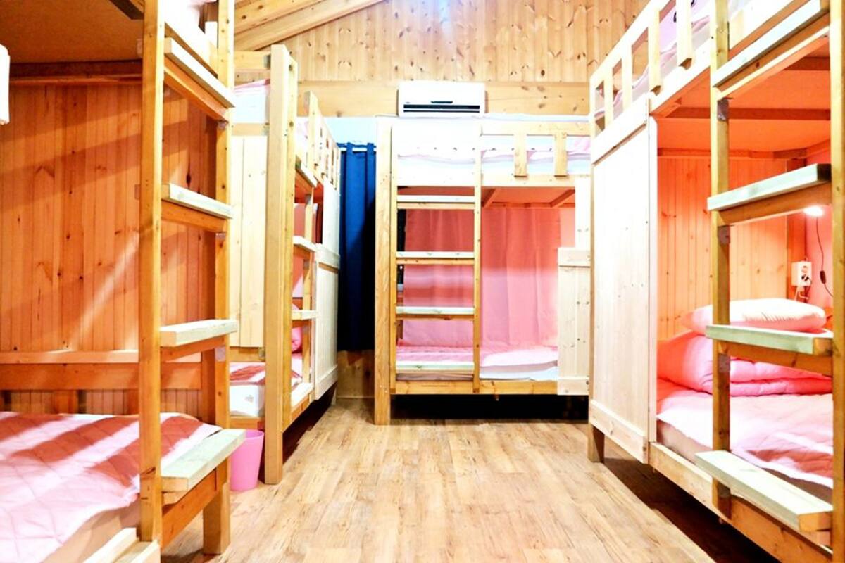 A wooden bunk bed room with a central door, wooden walls, and a wooden floor.