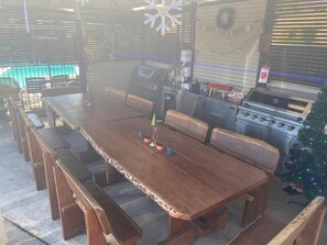 Une table de salle à manger en bois, avec des bancs, un barbecue et un sapin de Noël.