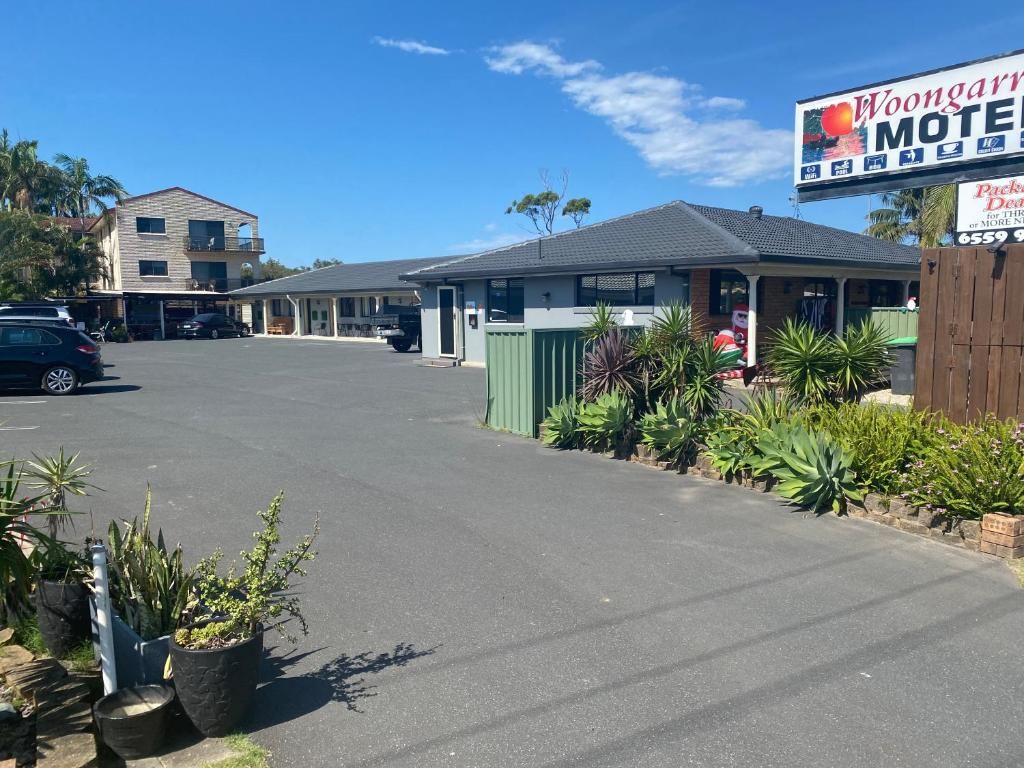 A motel with a signboard, a parking lot, and potted plants.