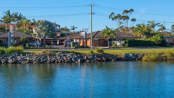 A motel with a swimming pool, surrounded by palm trees and a clear blue sky.
