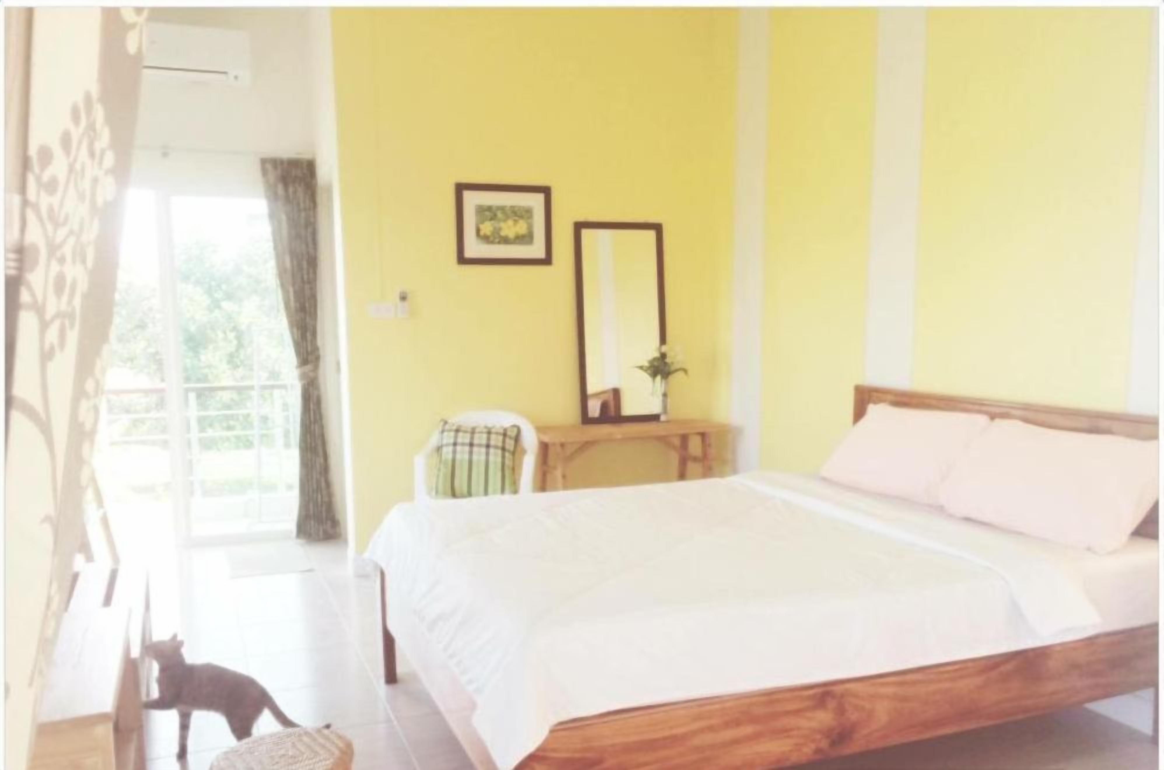 A double room with a bed, a chair, a small table, a mirror, and a window with curtains.
