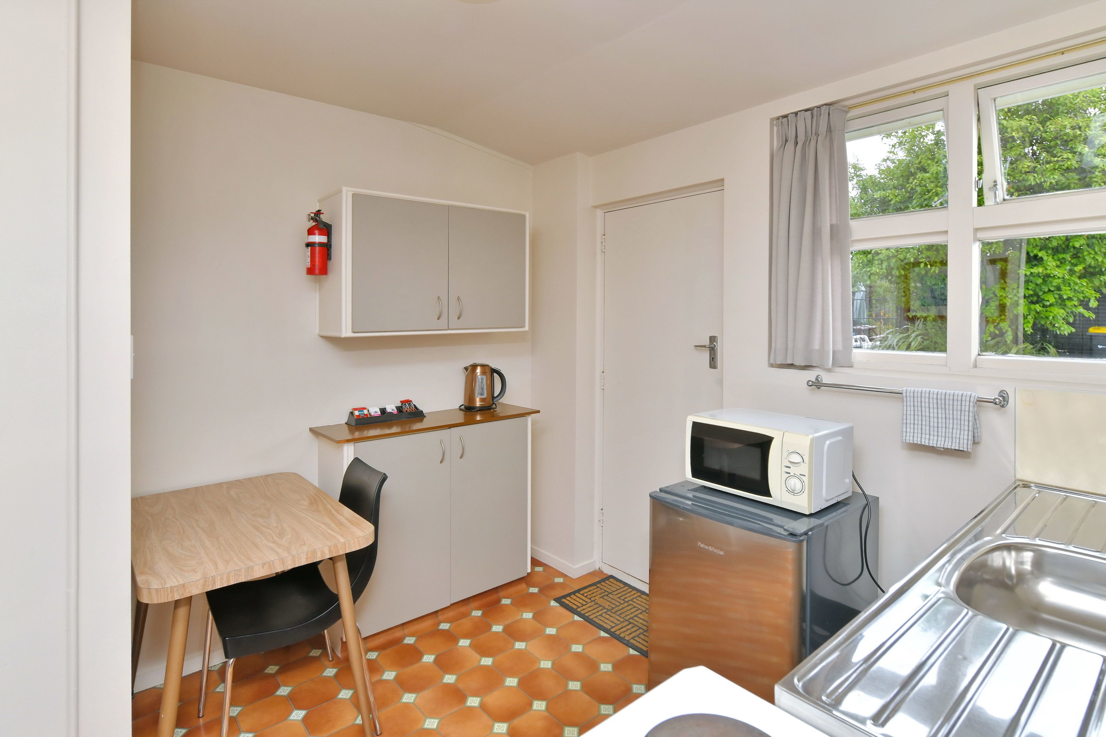A compact kitchen with a microwave, a kettle, and a sink.