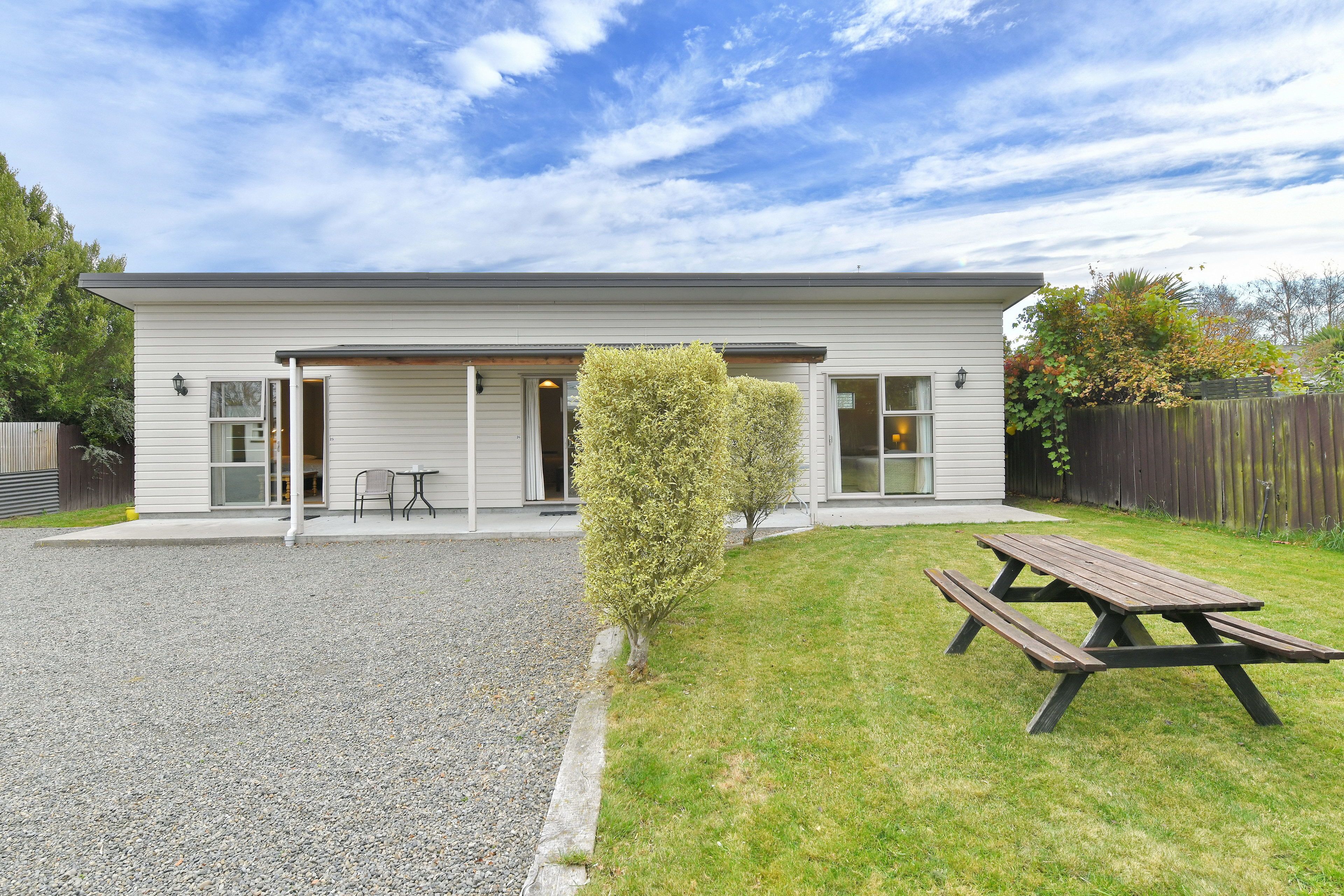 A two-story house with a covered patio area, a wooden deck, and a small lawn.
