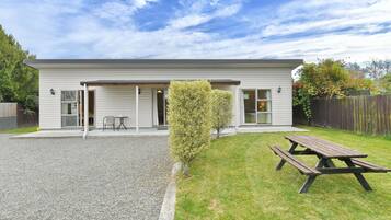 A two-story house with a covered patio area, a wooden deck, and a small lawn.