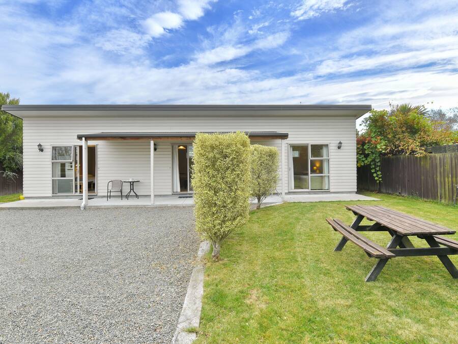 A two-story house with a covered patio area, a wooden deck, and a small lawn.