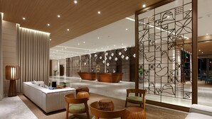 Eine moderne Lobby mit Empfangstresen, Sitzgelegenheiten und dekorativen Wandverkleidungen.