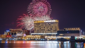Ein Hotel mit auffälliger Beschilderung, Blick auf das Wasser und einem Feuerwerk.
