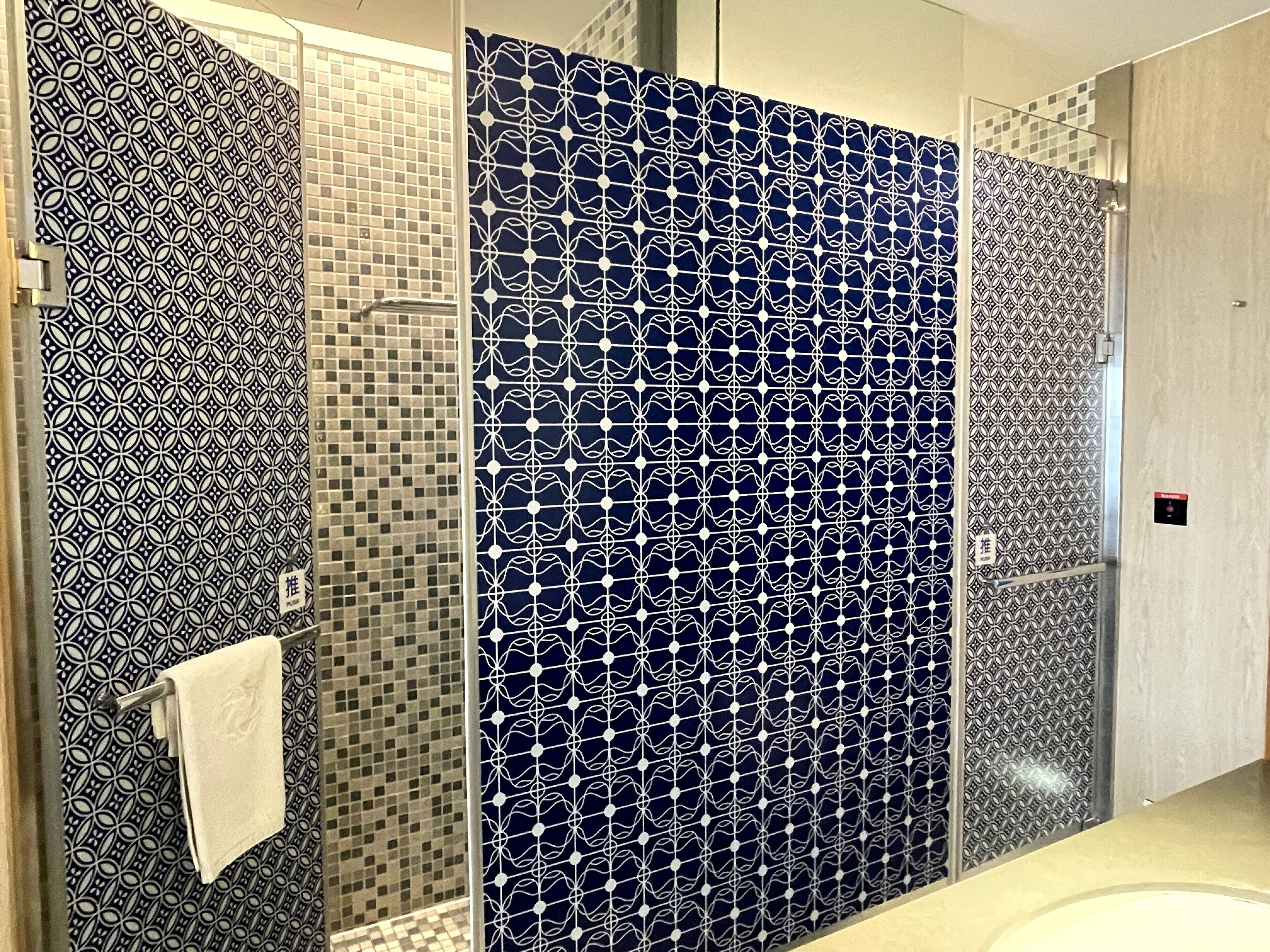 A bathroom with patterned tiles, a glass shower enclosure, and a towel rack.