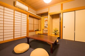 Una habitación japonesa tradicional con suelo de tatami, una mesa de madera baja y puertas correderas.