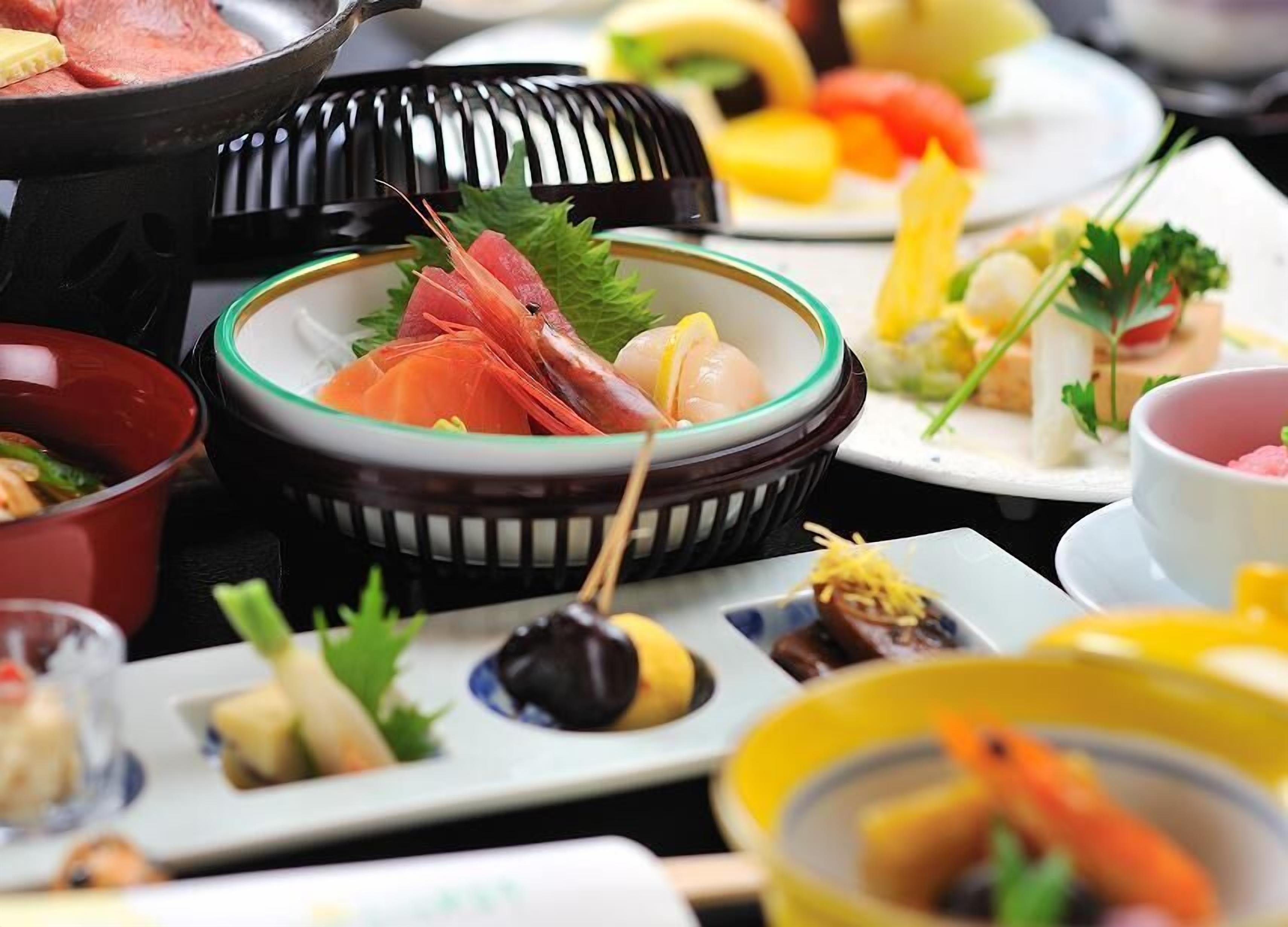 Une variété de plats, notamment des sashimis et d’autres mets, disposés sur une table.