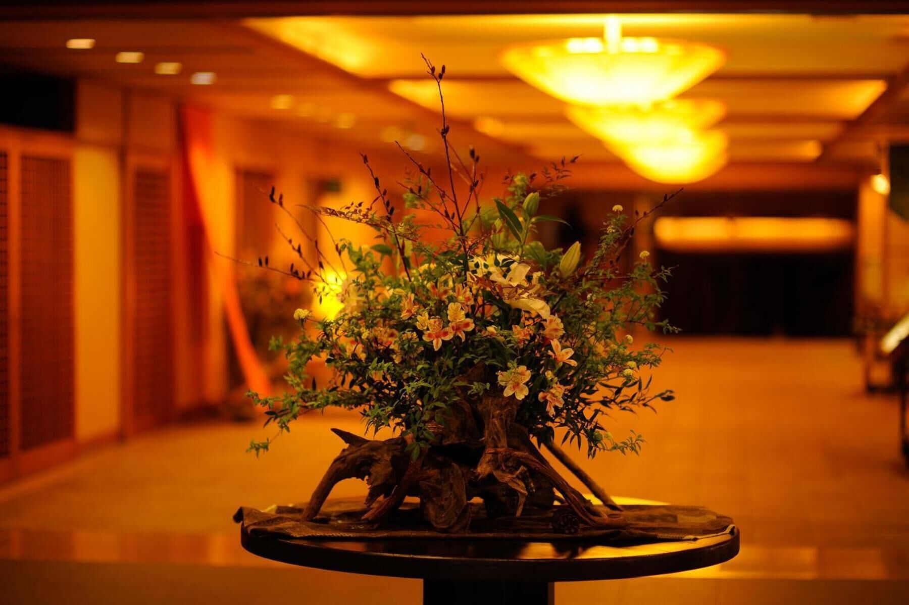 A lobby with a round table featuring a floral arrangement and a decorative tree trunk centerpiece.