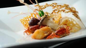 Een zeevruchtengerecht met krab, paddenstoelen en andere ingrediënten, gepresenteerd op een wit bord.