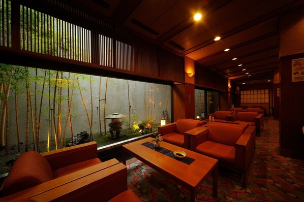 A traditional Japanese-style room with tatami flooring, low wooden tables, and red cushioned seating.