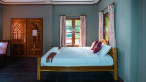 Una habitación con una cama y una puerta de madera, y una ventana con cortinas.