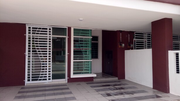 A covered outdoor area with a tiled floor, a white door, and a green window. - Khalish Homestay (Chemor)