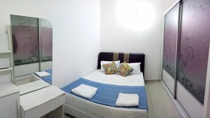A neatly arranged bedroom with a bed, a bedside table, a mirror, and a wardrobe. - Khalish Homestay (Chemor)