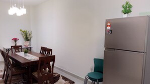 A dining area with a wooden table, chairs, a refrigerator, and a ceiling fan. - Khalish Homestay (Chemor)