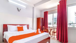 Ein Hotelzimmer mit einem großen Bett, einem kleinen Tisch und Blick auf die Stadt durch das Fenster.
