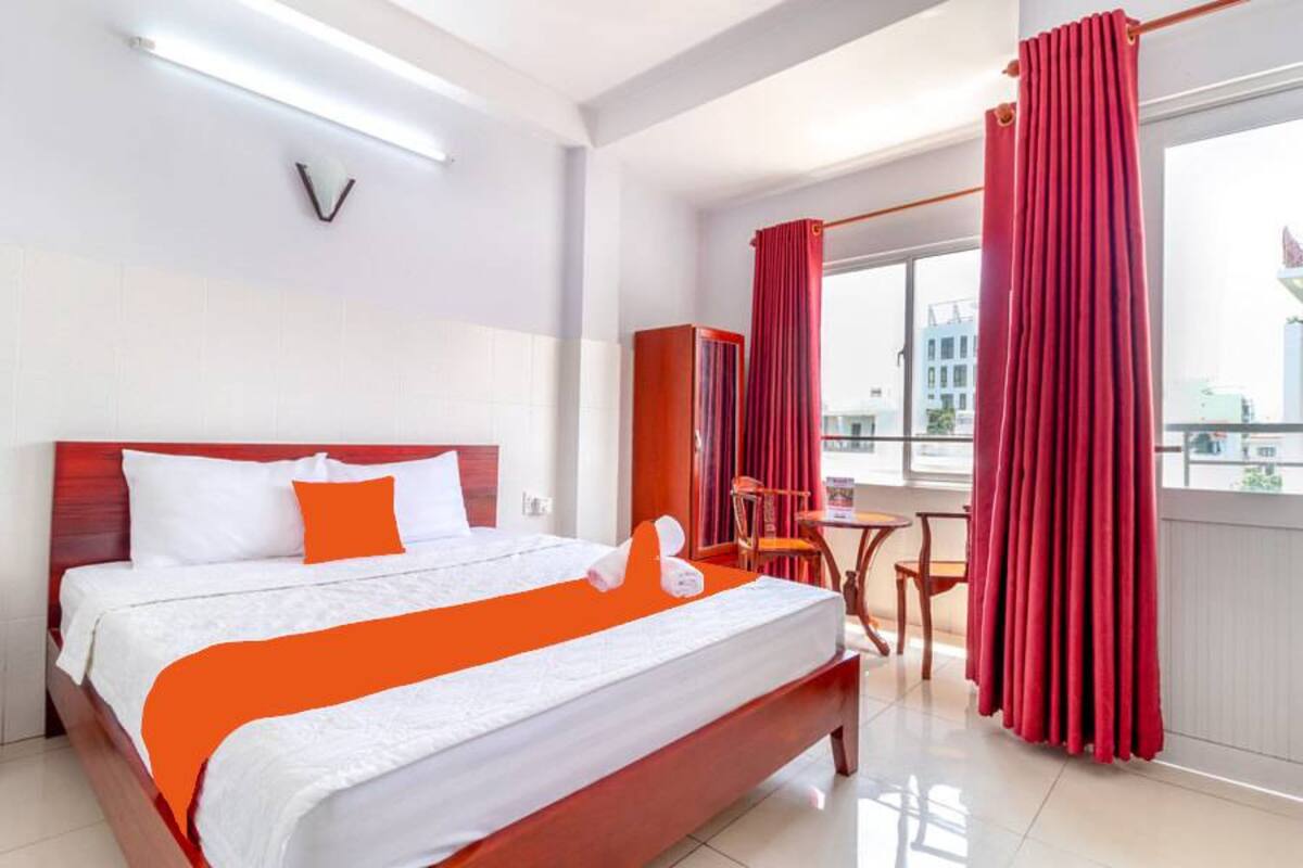 Une chambre d’hôtel avec un grand lit, une petite table et une vue sur la ville par la fenêtre.