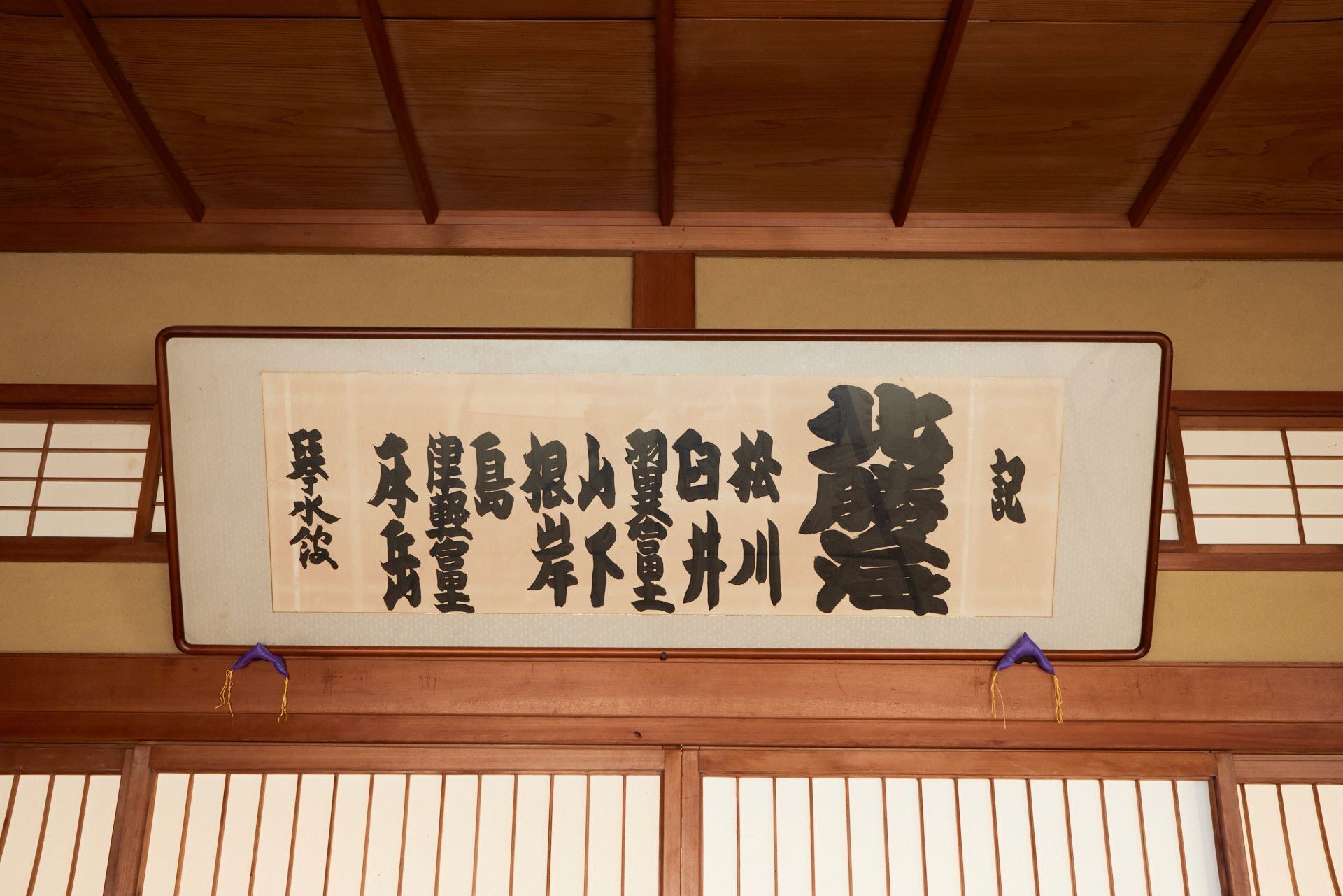 Een traditionele Japanse kamer met tatami vloerbedekking, een shoji schuifwand en een hangende scroll met kalligrafie.
