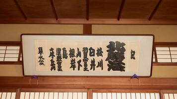 Een traditionele Japanse kamer met tatami vloerbedekking, een shoji schuifwand en een hangende scroll met kalligrafie.