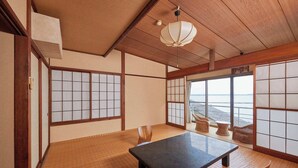 Een traditionele Japanse kamer met tatami vloeren, shoji schermen, een lage tafel en uitzicht op zee.