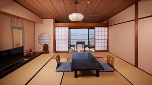 Een traditionele Japanse kamer met tatami vloerbedekking, een lage tafel en een televisie.