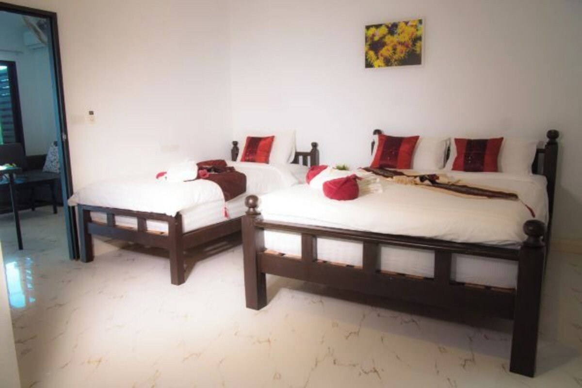 A double bed with a wooden frame, white bedding, and red and white pillows.